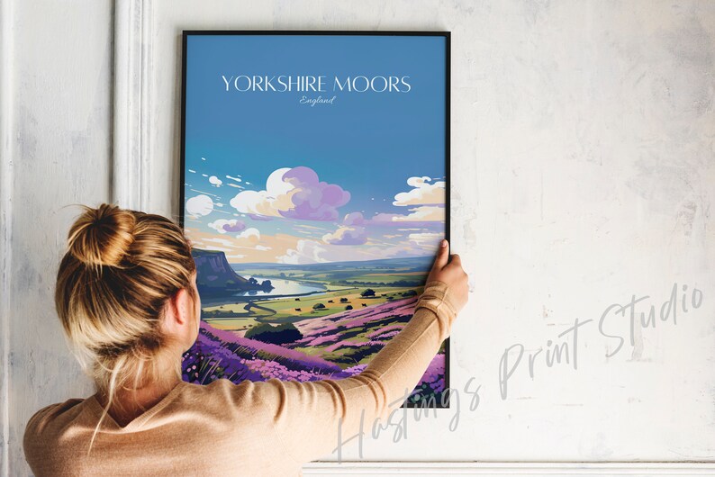 Może przedstawiać: Ramka z plakatem przedstawiającym kolorową ilustrację krajobrazu z fioletowymi kwiatami i rzeką. Plakat zawiera tekst "YORKSHIRE MOORS England" u g&oacute;ry.