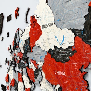 Peut inclure: Une carte du monde en bois détaillée avec des pays de différentes couleurs. La Russie est blanche, la Chine est rouge et la Mongolie est noire. La carte comprend les noms des pays et les étiquettes des villes, avec l'accent sur le continent asiatique.