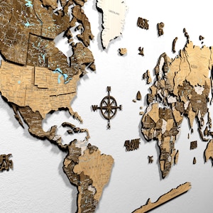 May include: A detailed wooden world map with a compass rose in the center. The map features continents and countries in varying shades of brown, with blue accents for water bodies. The United States of America is labeled.
