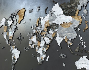 Puede incluir: Un mapa del mundo de madera con países en tonos grises, marrones y negros. El mapa incluye etiquetas para océanos y continentes, con nombres de países como Rusia y China. Se incluyen recortes decorativos de aviones y barcos.