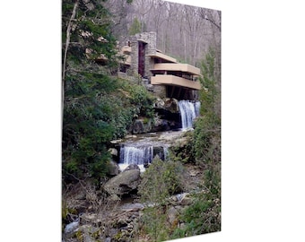 May include: A modern, concrete and wood house built over a waterfall in a wooded area. The house has a cantilevered design and is surrounded by lush greenery.