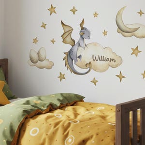May include: A child's bedroom with a wooden bed frame and bedding in shades of yellow and green. The wall features a whimsical mural of a dragon, clouds, stars, and a crescent moon. The name "William" is written on a cloud.