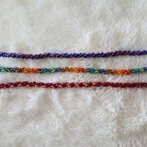May include: Three beaded bracelets in a variety of colors, including purple, orange, teal, and red. The bracelets are made with small, colorful beads and have silver clasps.
