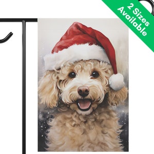 May include: A garden flag featuring a smiling, light brown dog wearing a red Santa hat with white trim. The dog has a pink nose and is set against a snowy background. The flag is displayed on a black metal stand. Text on the flag reads "2 Sizes Available".