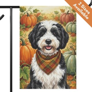 May include: A rectangular garden flag featuring a black and white dog wearing a plaid bandana, positioned in front of a background of orange and green pumpkins and autumn leaves. The text 2 Sizes Available is printed in the top right corner.