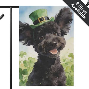 May include: A watercolor garden flag featuring a black poodle wearing a green leprechaun hat with a gold buckle. The dog is smiling with its tongue out, surrounded by green shamrocks. The background is a light blue sky.