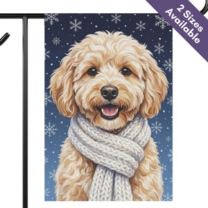May include: A rectangular garden flag featuring a fluffy, light brown Goldendoodle dog wearing a thick, white cable-knit scarf. The background is a deep navy blue color decorated with white snowflakes of various sizes. The text 2 Sizes Available appears.