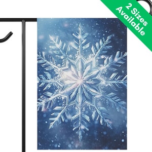 May include: A winter-themed garden flag featuring a detailed, close-up image of a large, icy blue snowflake. The snowflake has intricate crystalline structures, set against a blurred, snowy background. The flag is displayed on a black metal stand.