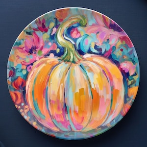 May include: A decorative plate featuring a vibrant, impressionistic painting of a pumpkin. The pumpkin is rendered in shades of orange, yellow, and blue, with a green stem. The background is filled with colorful floral elements in pink, blue, and orange.