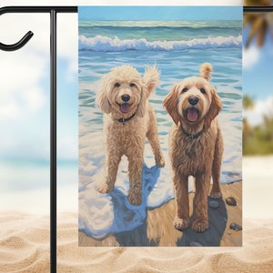 May include: Two golden doodle dogs stand in the ocean waves on a sandy beach. The dogs are smiling and looking at the camera. The water is blue and there are white waves crashing on the shore.