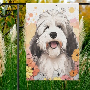 May include: A white and gray dog with a black nose and brown eyes is surrounded by colorful flowers. The dog is smiling and has a happy expression. The background is a light yellow with white dots.