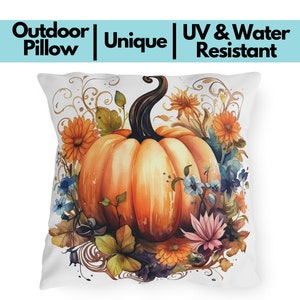 May include: White outdoor pillow with a watercolor design featuring a large orange pumpkin surrounded by orange, blue, and pink flowers. The pillow has the text "Outdoor Pillow | Unique | UV & Water Resistant".