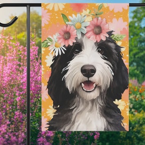 May include: A black and white doodle dog wearing a flower crown with pink, white, and yellow flowers. The dog is on a yellow background with a floral pattern.