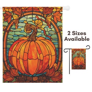 May include: A stained glass style garden flag featuring a large orange pumpkin with a leafy vine. The pumpkin is surrounded by a decorative frame with a blue and green background.