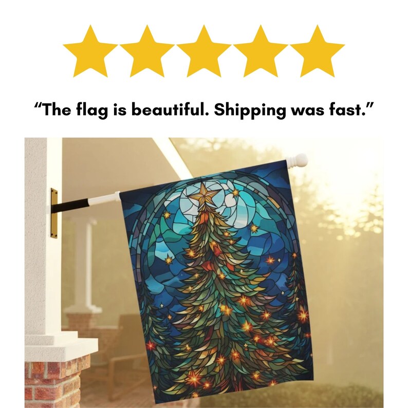 May include: A decorative outdoor flag featuring a stained-glass design of a Christmas tree, a star, and a moon against a dark blue night sky. The flag is hanging from a white pole and is mounted on a white brick column.