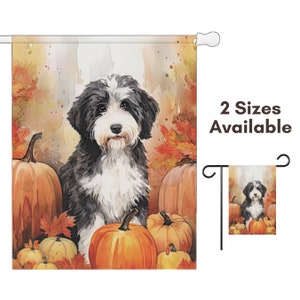May include: A decorative garden flag featuring a watercolor painting of a black and white dog sitting among pumpkins and fall foliage. The flag is rectangular and includes the text "2 Sizes Available".
