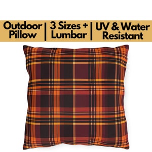 May include: Square outdoor pillow with a plaid pattern in shades of orange, burgundy, and black. The pillow has a white background and text that reads "Outdoor Pillow | 3 Sizes + Lumbar | UV & Water Resistant".