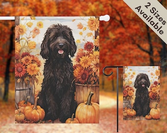 May include: A garden flag featuring a black dog sitting among pumpkins, sunflowers, and wooden barrels. The background shows an autumn scene with fall foliage. The flag is available in two sizes.