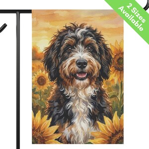 May include: A rectangular garden flag featuring a watercolor illustration of a tricolor Bernedoodle dog with black, brown, and white fur, surrounded by yellow sunflowers against a warm orange sunset background. The text 2 Sizes Available is visible.