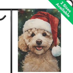 May include: A garden flag featuring a watercolor painting of a smiling, light brown dog wearing a red and white Santa hat. The background is a dark green with hints of red berries and snow. The flag is attached to a black metal stand.