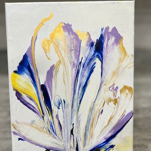 Puede incluir: Pintura abstracta sobre lienzo con patrones en espiral en tonos de blanco, morado, azul y dorado. La pintura se muestra en un pequeño caballete.