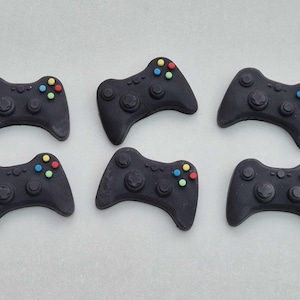 May include: Six black plastic game controllers with colourful buttons. The controllers are arranged in two rows of three.