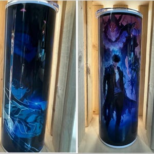 Könnte beinhalten: Zwei Edelstahlbecher mit einem schwarzen und blauen Anime-Charakterdesign. Der Becher links zeigt einen Charakter mit blauen Haaren und einem schwarzen Outfit. Der Becher rechts zeigt einen Charakter mit schwarzen Haaren und einem schwarzen Outfit. Beide Becher haben einen weißen Hintergrund.