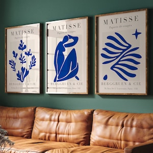 Może przedstawiać: Trzy oprawione wydruki artystyczne z turkusowym tłem. Wydruki przedstawiają niebieskie abstrakcyjne kształty i tekst "MATISSE Papiers de coupes BERGGRUEN & CIE 26, Rue de L'Universite, Paris-VII".