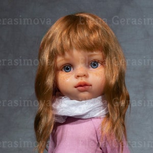 May include: A doll with long, wavy, auburn hair, wearing a pink dress, white scarf, and brown boots. The doll is sitting on a wooden box.