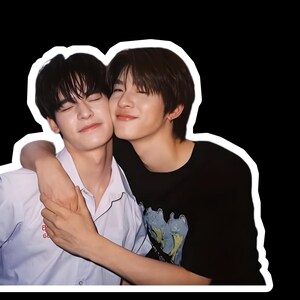 May include: A photograph of two young people embracing, with a white border. One wears a white collared shirt, the other a black t-shirt. Both have dark hair and are smiling with their eyes closed, conveying a sense of closeness.
