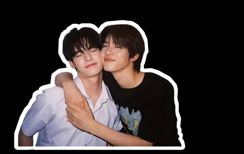 May include: A photograph of two young people embracing, with a white border. One wears a white collared shirt, the other a black t-shirt. Both have dark hair and are smiling with their eyes closed, conveying a sense of closeness.