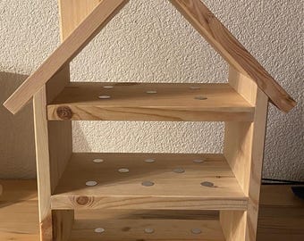 May include: A wooden house-shaped shelf with three shelves. The shelves are decorated with small silver circles.