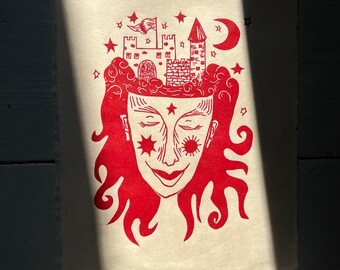 May include: Red linocut print of a person with a castle on their head. The castle has a flag and a crescent moon is in the sky above. The person has stars in their eyes and a happy expression.