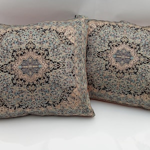 Può includere: Due cuscini decorativi con un design a motivi blu, nero e beige. I cuscini presentano un motivo geometrico ripetitivo con un motivo floreale centrale.