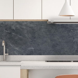 Peut inclure: Une cuisine moderne avec des armoires blanches, un plan de travail moucheté et une crédence gris foncé. Un robinet en acier inoxydable et une suspension blanche sont également visibles. L'esthétique est épurée et contemporaine.
