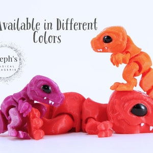 May include: Three articulated dinosaur toys in the image. One is red, one is purple, and the other is orange. The toys have black eyes and are on a white background. The text "Available in Different Colors" is at the top.