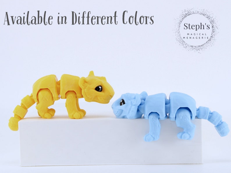 May include: Two small, articulated animal figurines, one yellow and one blue, are posed on a white surface. The yellow figurine is a tiger and the blue figurine is a bear. The text "Steph's Magical Menagerie" is visible in the background.