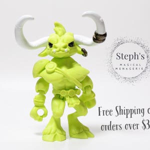 May include: A lime green action figure of a horned creature with white horns and a stern expression. The figure has armor-like details and is posed against a white background. The text "Steph's Magical Menagerie" is visible.