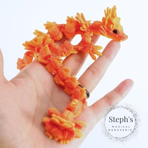 Pu&ograve; includere: Una statuetta di drago articolata di colore arancione e giallo brillante. Il drago &egrave; in posizione arrotolata con la testa alzata. La statuetta &egrave; realizzata in un materiale flessibile e misura circa 25 cm di lunghezza.