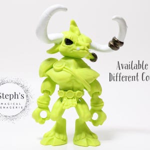 May include: A lime green figurine of a horned creature with white horns and dark accents. The figure has a muscular build and is posed upright. Text on the image says "Available in Different Colors."
