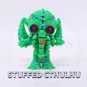 Könnte beinhalten: Eine grüne, gefüllte Cthulhu-Figur mit blauen Nähten und Knopfakzenten. Die Figur hat große, runde Augen mit lila und roten Details. Der Text "STUFFED CTHULHU" wird darunter angezeigt.
