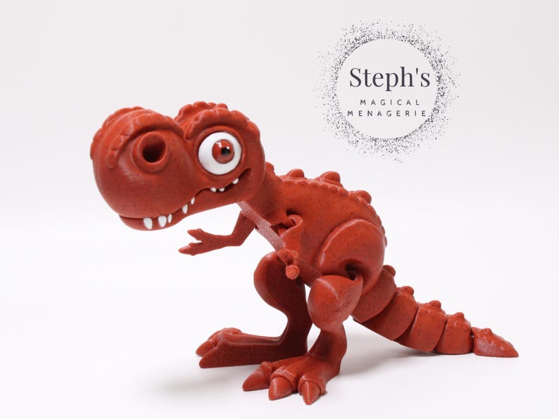 May include: A red, articulated, cartoon-style dinosaur toy with a large, white eye and a toothy grin. The toy is posed in a standing position with its tail curled around its body.
