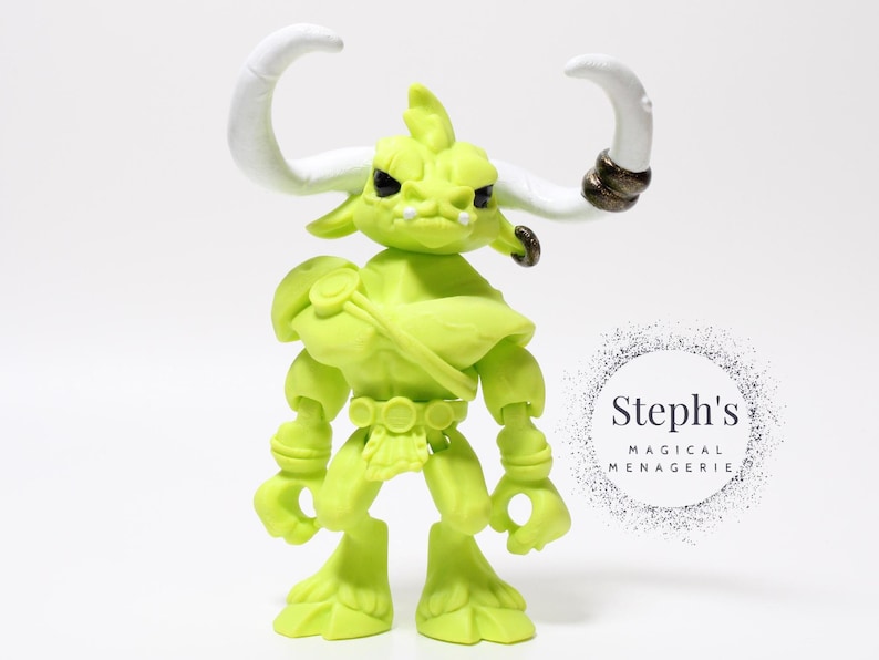 May include: A lime green figurine of a bull-like creature with large white horns and a stern expression. The figure has a muscular build and is wearing a belt and shoulder armor. The figure is approximately 5 inches tall.