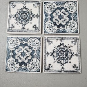 May include: Set of four square ceramic coasters with a white background and blue and black intricate floral patterns.