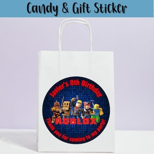 May include: White paper gift bag with a round sticker featuring Roblox characters. The sticker reads "Javier's 8th Birthday" and "Thank you for coming to my party!" in red text. The bag has a white handle and the text "Candy & Gift Sticker" at the top.