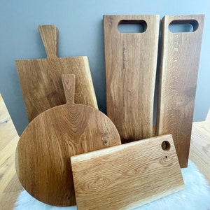 Puede incluir: Cinco tablas de cortar de madera de diferentes tama&ntilde;os y formas. Las tablas son de madera marr&oacute;n claro con un acabado natural. Algunas de las tablas tienen asas, mientras que otras tienen agujeros para colgar.