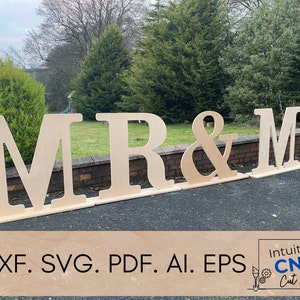 May include: Wooden letters spelling "MR & MR" in a garden. The letters are freestanding and have a natural wood finish. The letters are arranged in a line on the ground. The image includes the text "DXF. SVG. PDF. AI. EPS Intuitive CNC Cut Files".