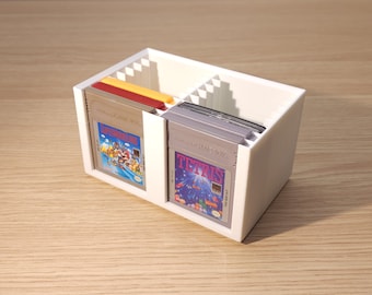 May include: White plastic storage case for video game cartridges. The case has two compartments, each with slots for multiple cartridges. The case is holding a variety of game cartridges, including "Super Mario Bros." and "Tetris".