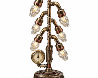May include: A table lamp constructed from bronze-toned metal pipes featuring six clear glass skull-shaped light bulbs. The base is a circular gear-like structure with an integrated analog clock face displaying black numerals and hands on a cream dial.