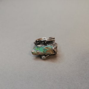 925 Sterling Silver ring with a one of a kind look.  The two black diamonds complete the look of this handmade item. The center piece is a rough opal.